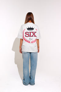 Person wearing a white t-shirt with 'SIX' design on the back, standing against a plain background