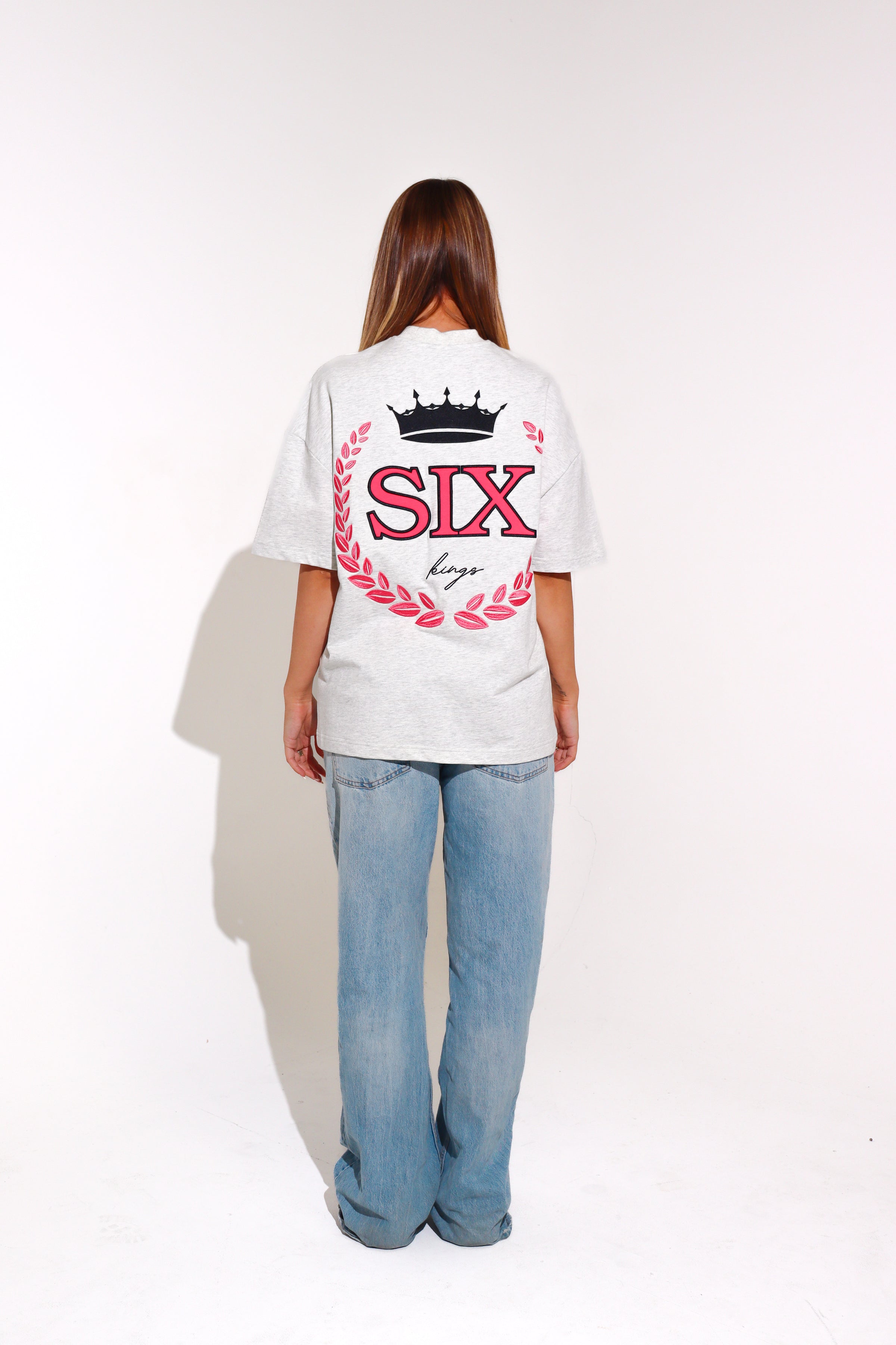 Person wearing a white t-shirt with 'SIX' design on the back, standing against a plain background