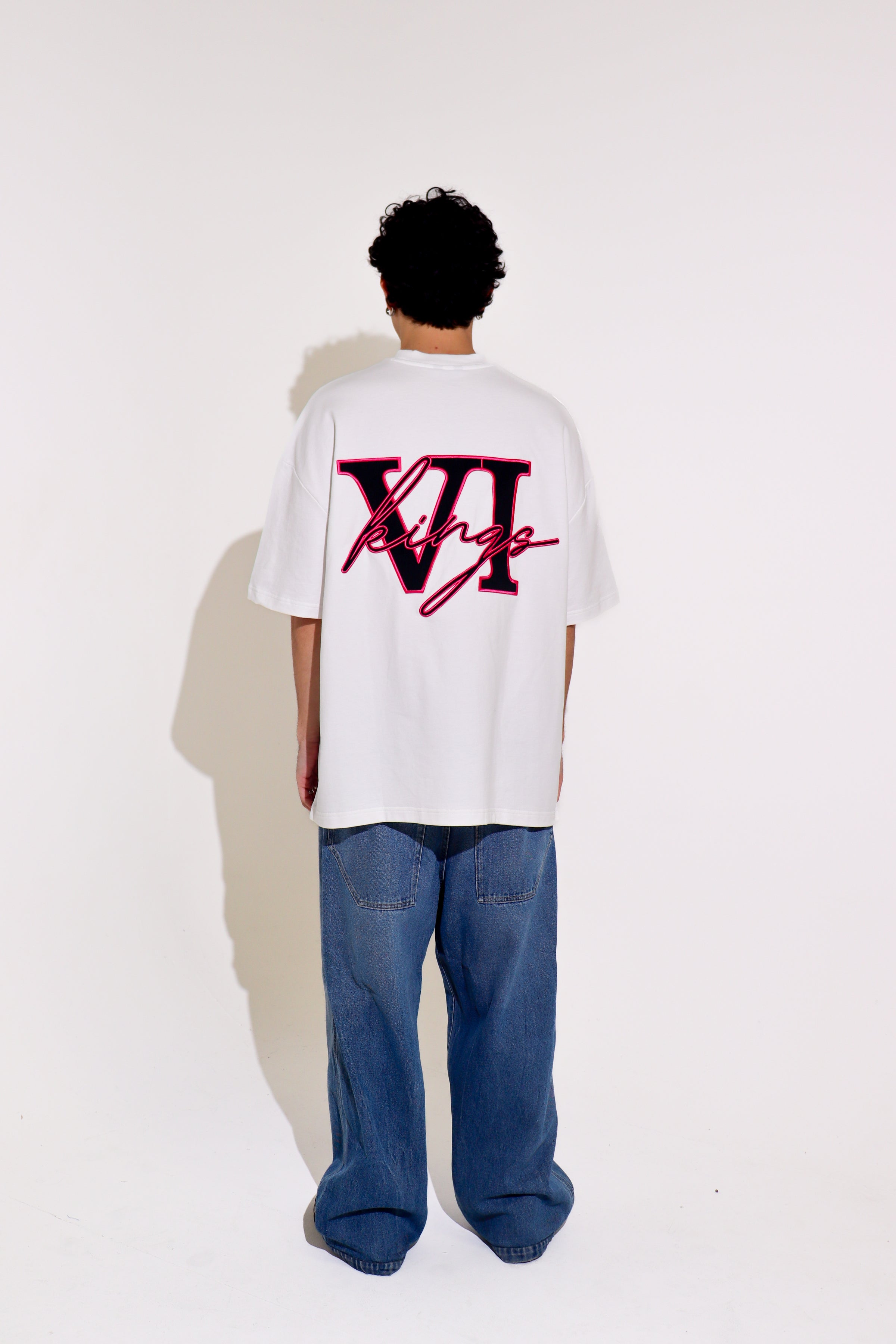 Person wearing a white t-shirt with a red logo on the back, standing against a white background